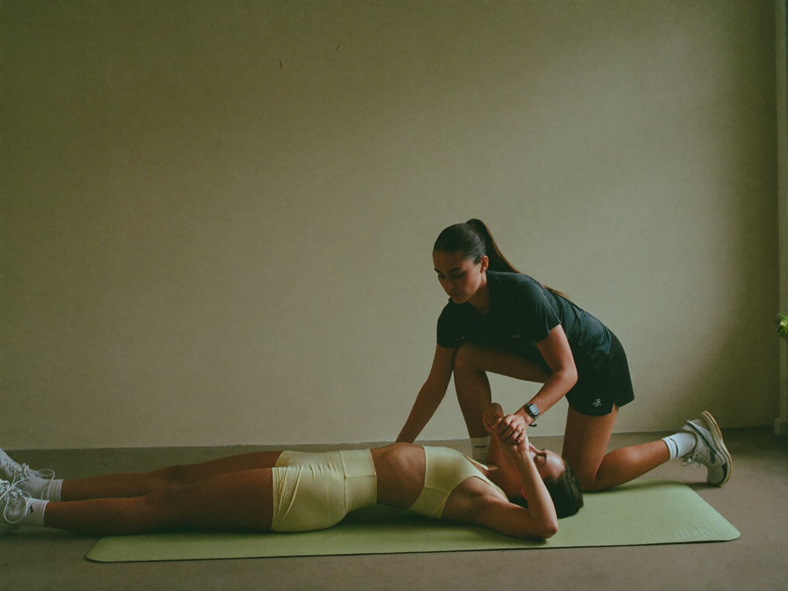 A coach guiding a client through a stretch in a bright studio